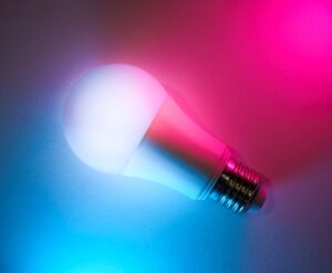 A vibrant LED light bulb with blue and pink neon lighting effects, showcasing smart home technology.