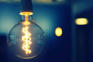 A close-up image of a glowing lightbulb with a warm tone against a blurred background.